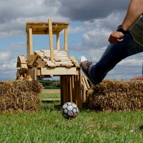 Ball fliegt durch Traktor-Hinderniss beim Fußball-Minigolf im Maislabyrinth Liederbach
