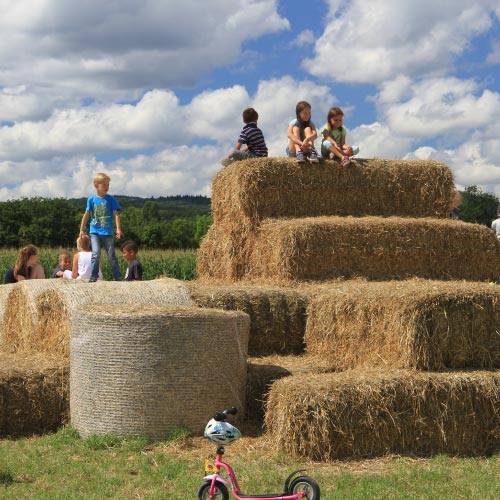 Kinder toben auf Strohballen im Maislabyrinth Liederbach